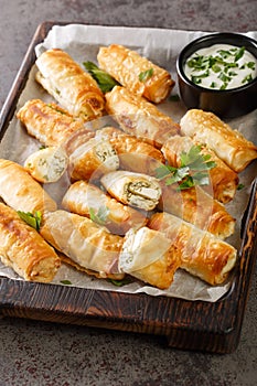 Sigara Boregi Turkish Cigar Shaped Rolls stuffed with cheese and herbs closeup on the wooden board. Vertical