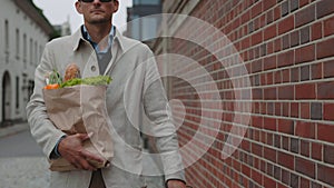 Sightless man carrying grocery bag while walking on street