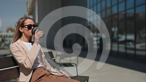 Sightless woman sitting on bench with coffee outdoors