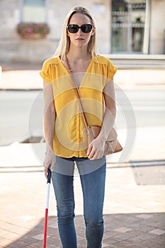 sightless woman walking alone using stick