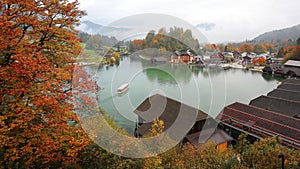 A sightseeing boat cruising on Konigssee ( King's Lake ) surrounded by colorful autumn trees and boathouses