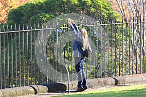 Sightseer stretching at iron fence for taking picture