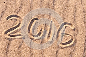 Sign 2016 and sun written on sandy beach. Summer travel concept