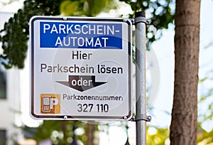 A sign above a parking ticket machine in a paid parking zone.