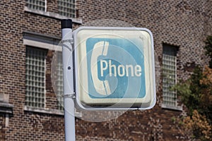 Sign for an ancient pay phone. Before cell phones in the 20th and early 21st centuries, people were forced to use pay phones