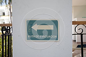 Sign with an arrow and a ruta de evacuacion - evacuation route - text on a white wall photo