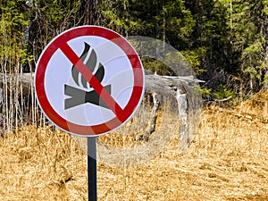 Sign ban bonfires on the background of forest and dry grass and trees.