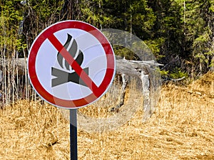 Sign ban bonfires on the background of forest and dry grass and trees. photo