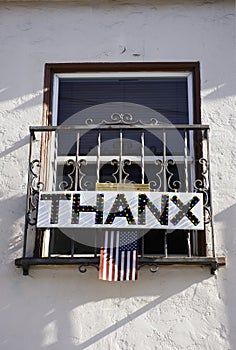 Sign banner from window saying thanks to health care workers. THANX hanging with USA flag.