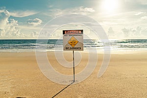Sign on the beach danger no swimming rip currents sunset lights