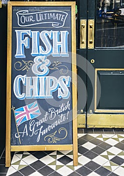 Sign on blackboard outside a pub in London promoting their Ultimate Fish and Chips, a great British favourite.