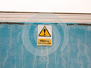 A sign on blue wall saying warning anti climb paint