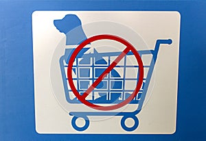 Sign in blue and white with graphic of a dog in a shopping cart indicating No Dogs Allowed In Shopping Carts