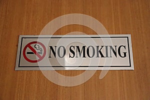 Sign board for no smoking is placed on the wooden surface.