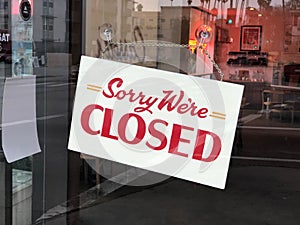 A Sign board of sorry we are closed hang on door of business shop with nature green background