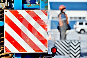 Sign is careful on trawling technique. Red white stripes on flat surface. Lifting cargo on street.