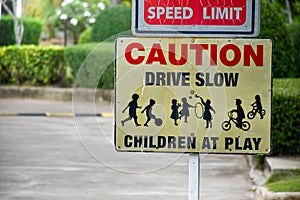 Sign caution speed limit drive slow children at play on yellow background at park in evening sunset, playground sign,landscape