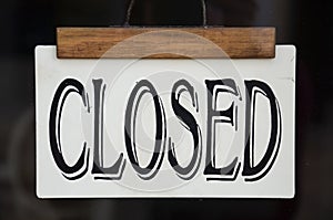 Sign Closed on the front window of a store. Black sign in Western-style font. Restaurants, bars and shops closed due to