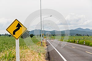 Sign curved road on the way at the natural  Field Or Meadow. Warning attention Right curve sign at Rural highway. Road sign showin