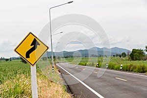 Sign curved road on the way at the natural  Field Or Meadow. Warning attention Right curve sign at Rural highway. Road sign showin