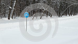 Sign `Cycle trail` against the background of snow-covered forest.