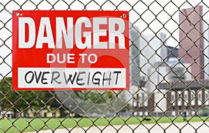 Sign danger due to overweight hanging on the fence