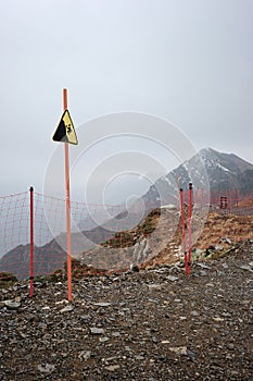 Sign danger of falling from a height on top of the mountain