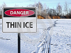 Sign danger thin ice and footprints road on snow and ice