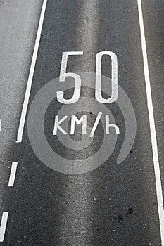 Sign on dark asphalt road 50 km in hour. Speed limit in European towns. Safety measures to reduce number of fatal accident