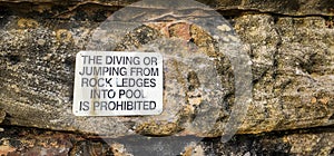 A sign about The diving or jumping from rock ledges into pool is prohibited photo