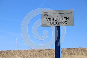 Sign with dutch text Verboden toegang which means in English no admittance of the water authority Delfland in the dunes of Monster