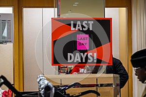 Sign in an empty bankrupt department store advertising the last day of sales.