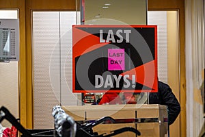 Sign in an empty bankrupt department store advertising the last day of sales.