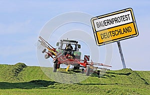 Sign with farmer protest Germany with a tractor mowing hay