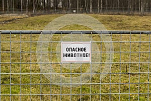 Sign on fence of empty outdoor corral reports of dangerous animal