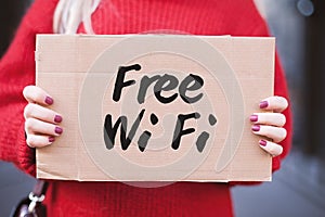 The sign `Free Wi-Fi` in the hands of the girl on a cardboard plate.