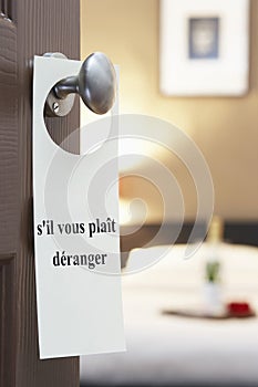 Sign with French text s'il vous plait deranger (please disturb) hanging on hotel room door