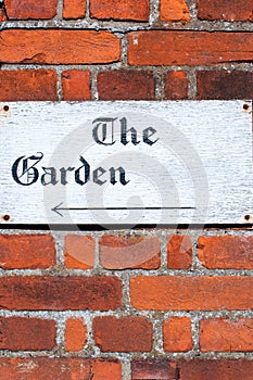 Sign for 'The Garden' on a brick wall background