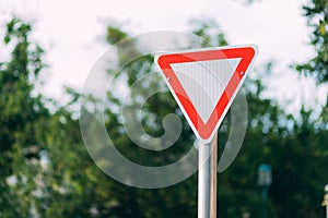 Sign give way on a blurred street and white sky.