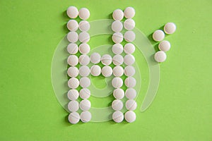 Sign H, for hospital, made by white pills on green background