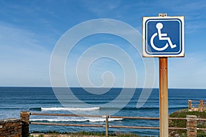 Sign for handicapped parking at a beach access with ocean behind photo