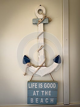 sign hanging from an anchor says Life is good at the beach