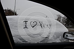 sign I love you on a parked snowy vehicle. one prank can mean divorce