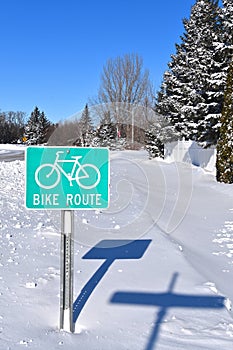 Sign indicating bike route under the snow