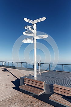 Sign indicating directions and distances to different cities of the world. The direction of the cities on the background of blue s