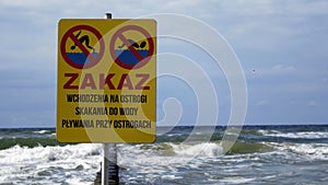 The sign informing about the prohibition of swimming and diving into the water in Polish at the seaside. photo