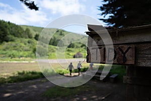 Sign labeled tidy sitting on wooden home on a farm with people walking in background