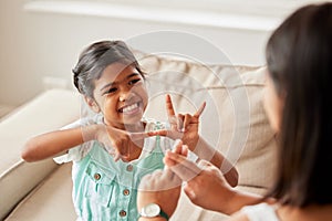 Sign language, communication and child with her mother in the living room of their family home. Happy, smile and girl