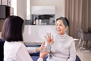 Sign language specialist talking with mature patient deaf hearing and showing hands gesture