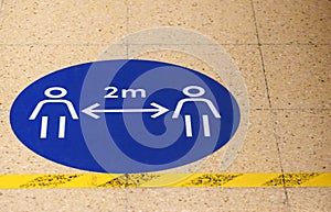 A sign / marker on a grocery supermarket shop floor showing the social distancing spacing of 2 metres photo